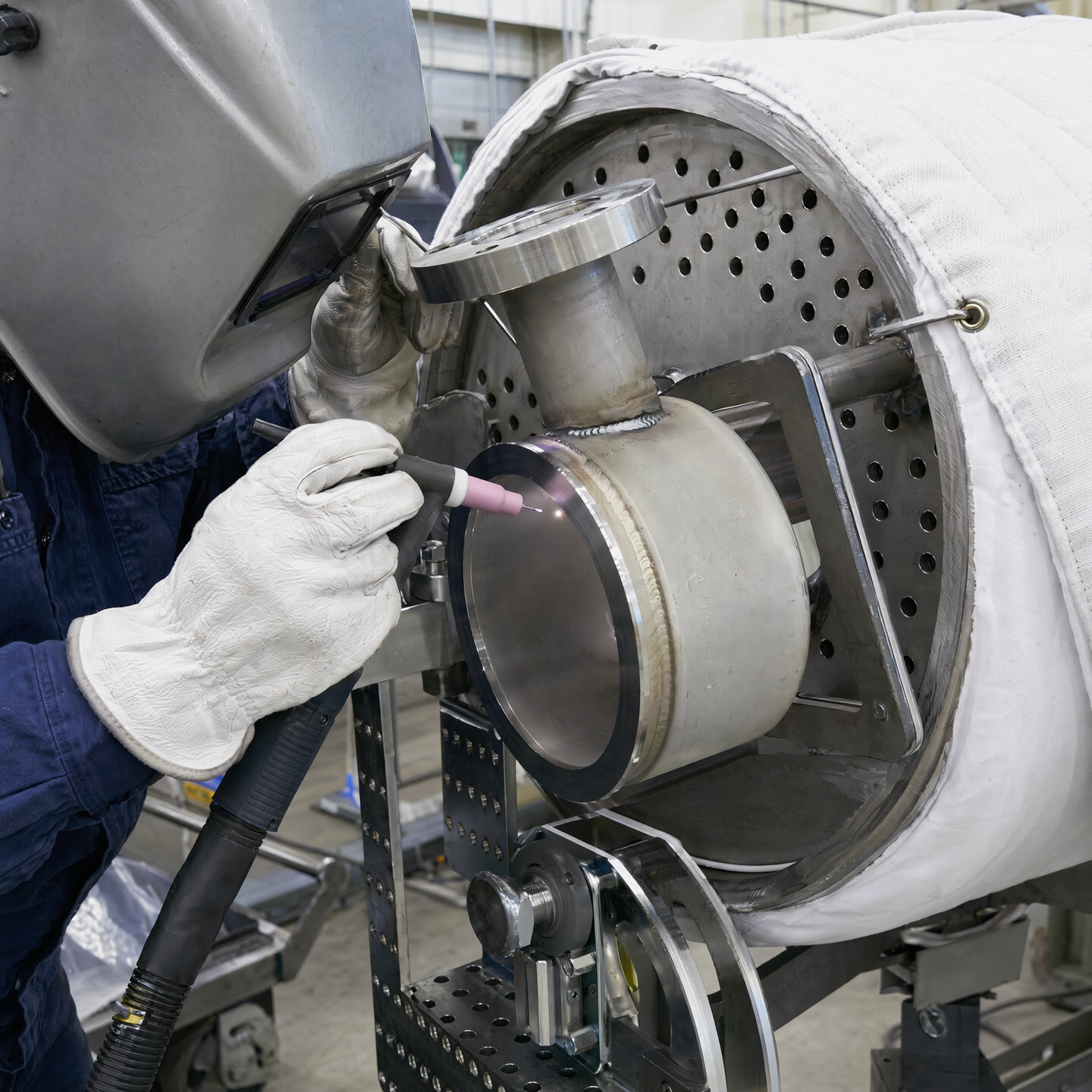 Fabricator carrying out a controlled connection weld on an exchanger assembly